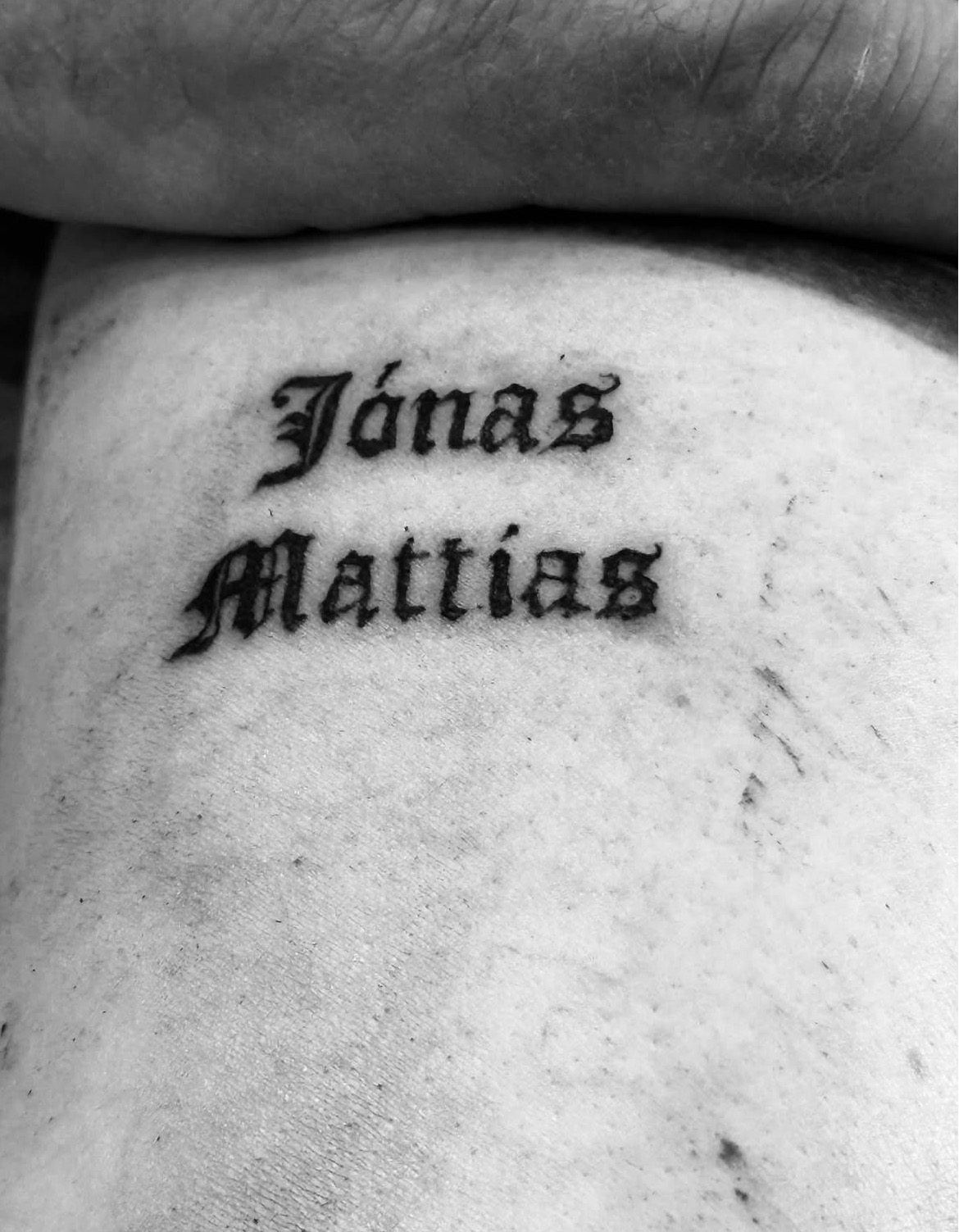 Blackletter lettering tattoo of the names Jónas and Mattias